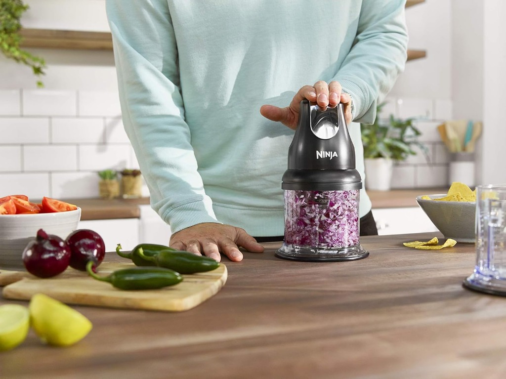 Ninja mini chopper chopping fresh herbs and red onions in a kitchen